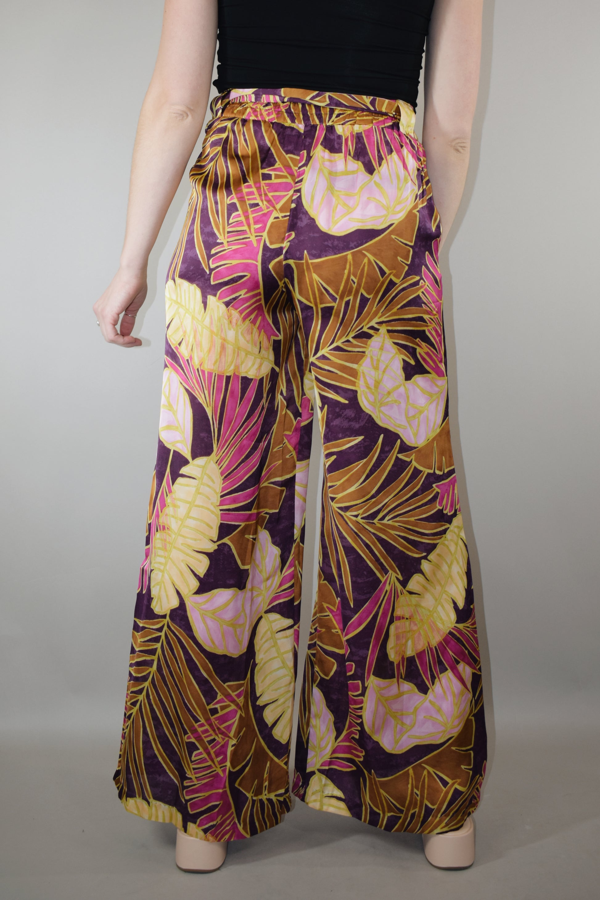 satin wide leg pants high waisted full length with elastic on back of waistband satin sash waist tie has beltloops and pockets tropical print with magenta cream and blush tones