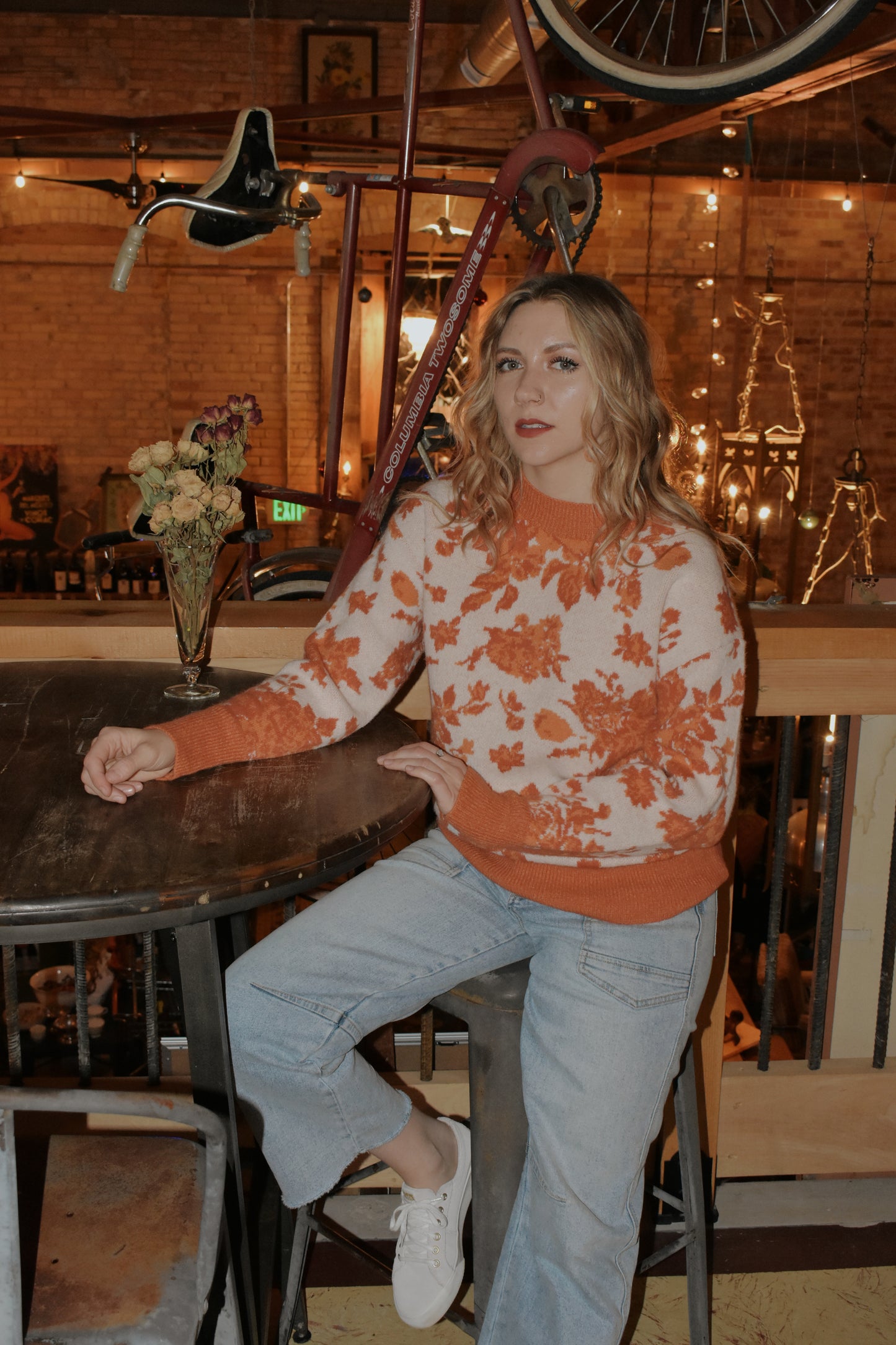 ivory and shades of orange high neck sweater with a leafy floral design. hemline neckline and cuffs are solid orange and ribbed. full length, relaxed fit, drop shoulder.