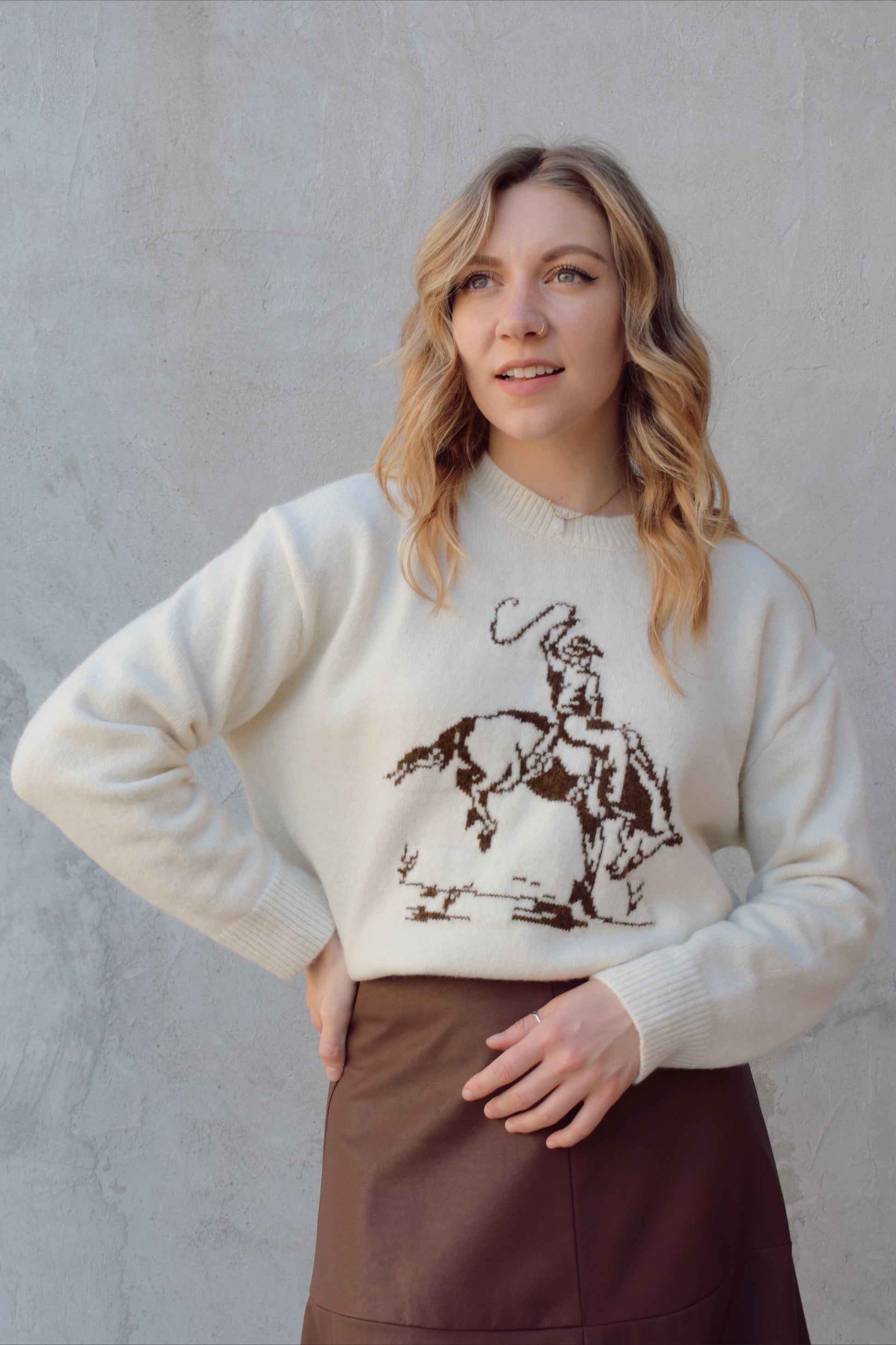 cream colored crew neck sweater relaxed fit full length with cowboy design in brown on front ribbed cuffs hem and neckline