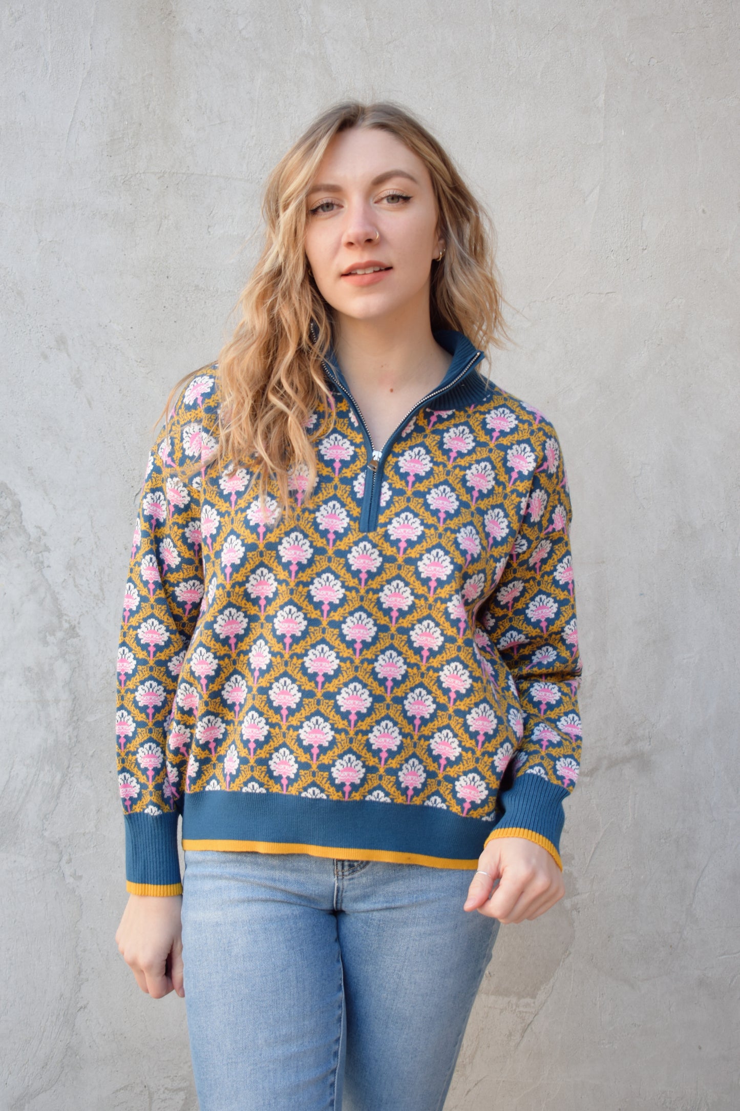 half zip relaxed fit statement pattern pullover with blue and yellow band at ham and cuff and just blue on collar. pattern is yellow, white, and pink on a blue background