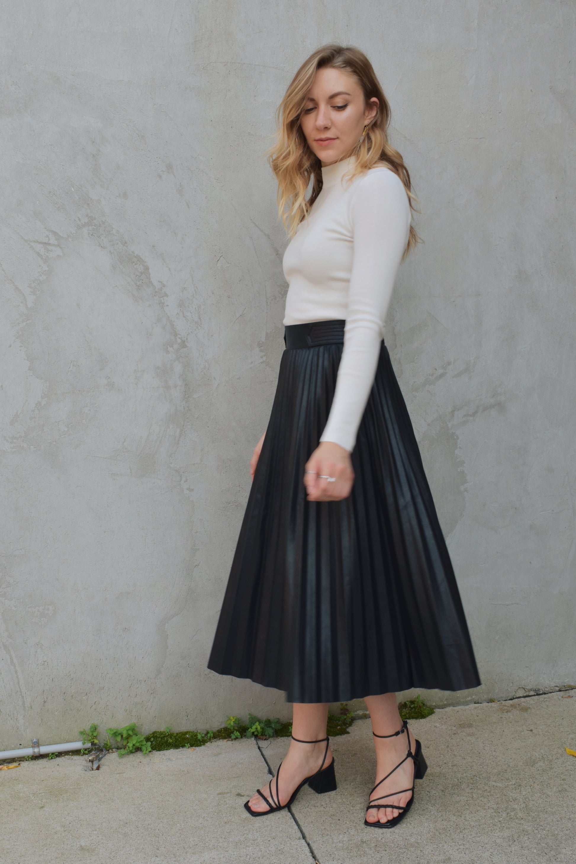 high waisted fully pleated faux leather skirt midi length waist band has tab detailing back of waistband has elastic in band for stretch and it has an invisible zip enclosure on the side