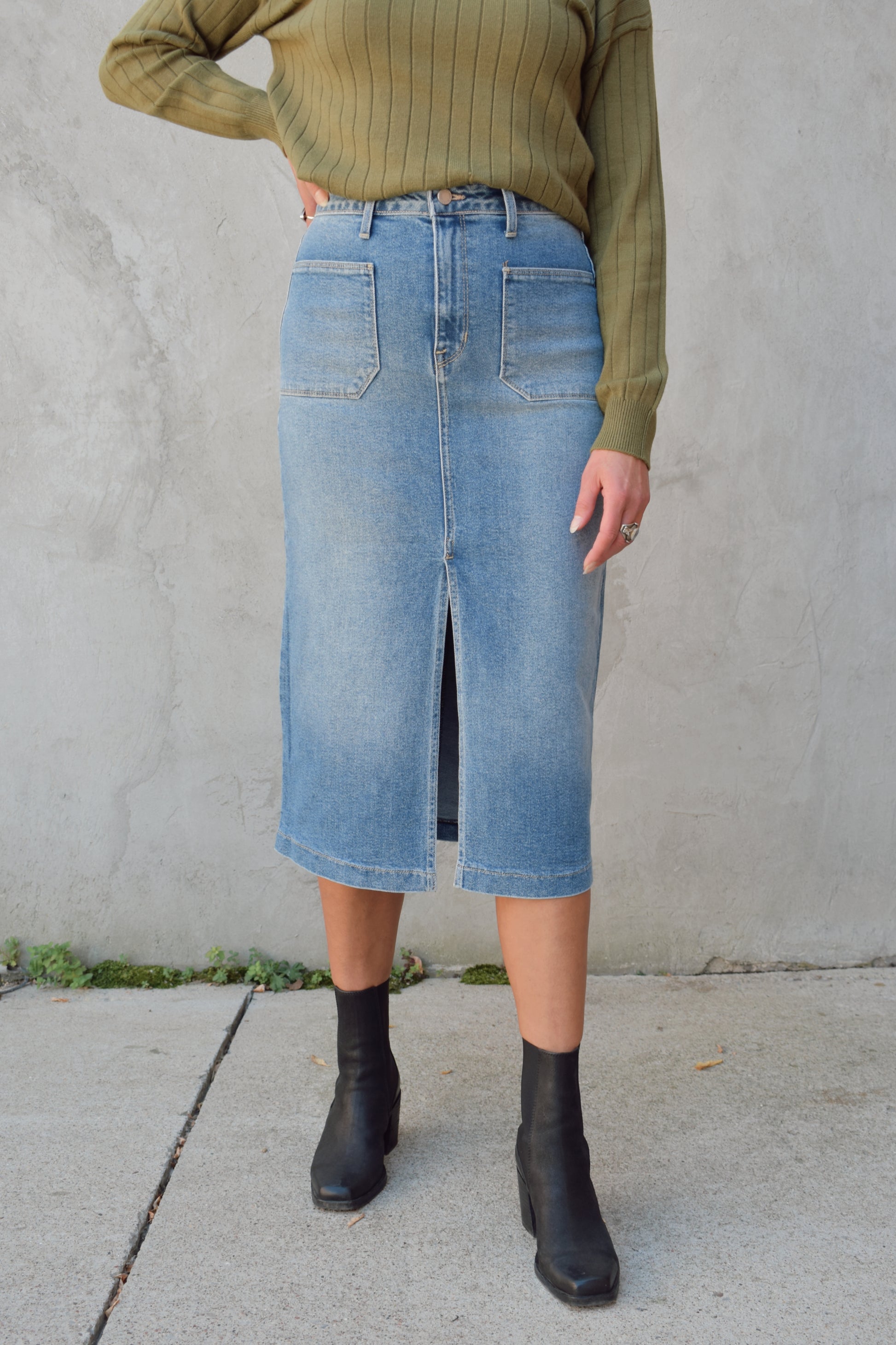 medium to light wash denim midi skirt with front slit, front patch pockets, zip and button enclosure, beltloops, back pockets, no distressing.