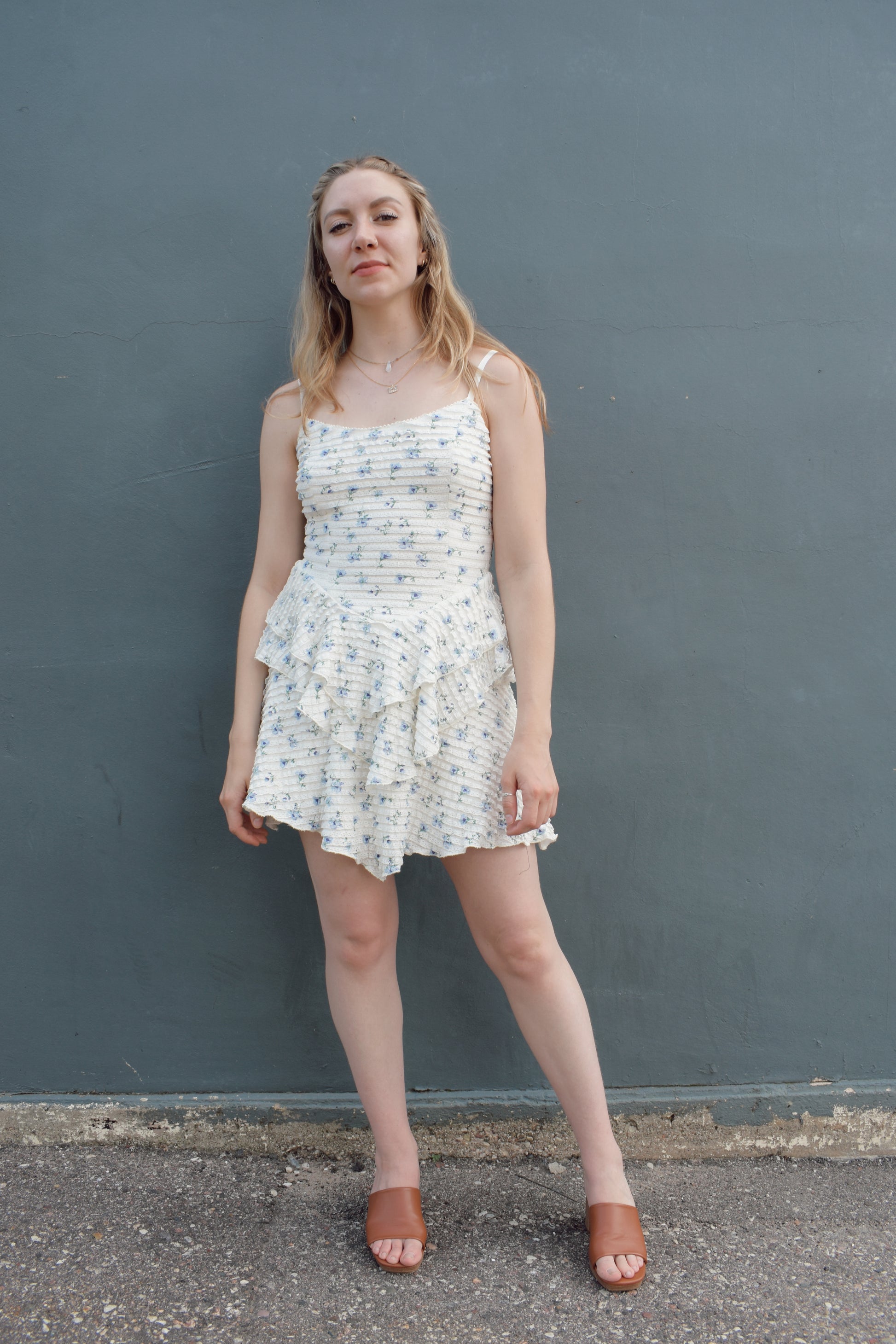cream mini dress with a blue ditsy floral pattern and mini ruffle fabric, stretchy, back zip enclosure, adjustable spaghetti straps, shark bite tiered skirt, fitted bodice, lined