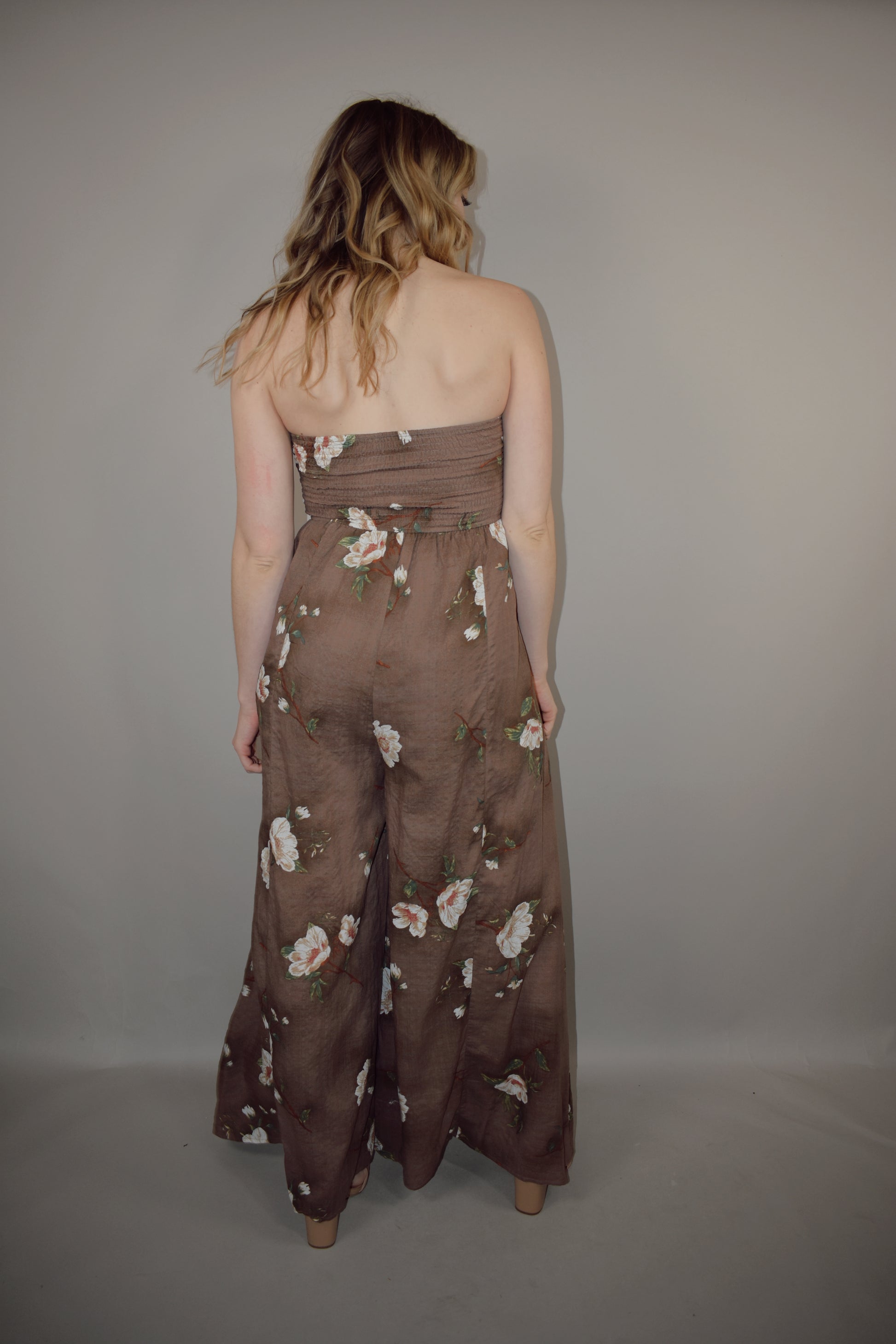 strapless wide leg flowy floral jumpsuit with tie and eyelet hole on front of bodice, has a elastic back panel on bodice full length, no pockets, is lined