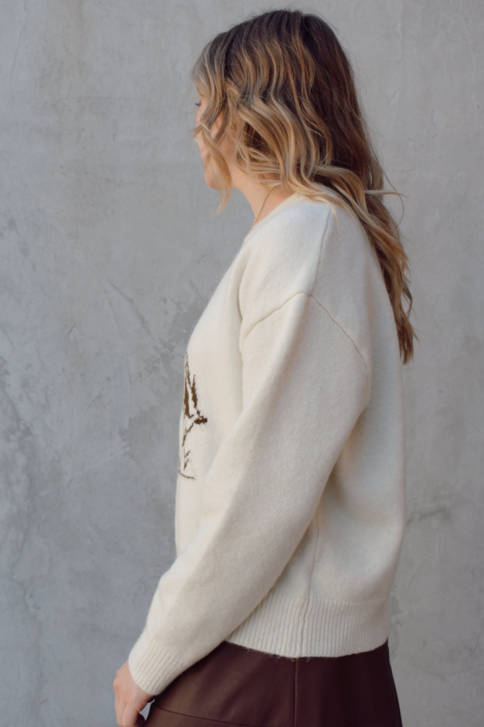 cream colored crew neck sweater relaxed fit full length with cowboy design in brown on front ribbed cuffs hem and neckline
