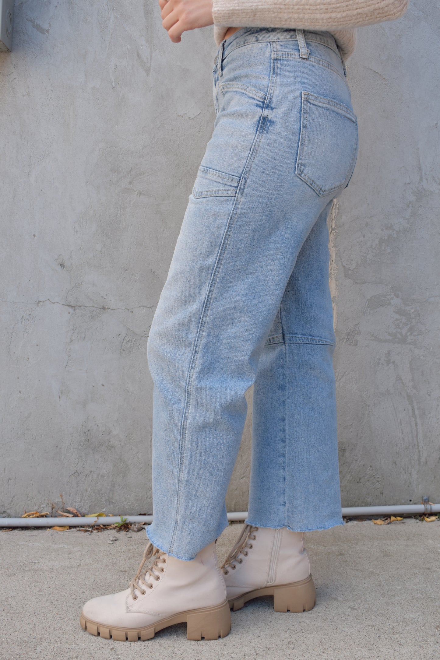 high rise barrel jeans, light wash, stretch denim, no holes, patch pockets in front, back pocket on right has a double pocket detail, zip and button enclosure, has belt loops, raw hem cropped, edgy seam detail at knee