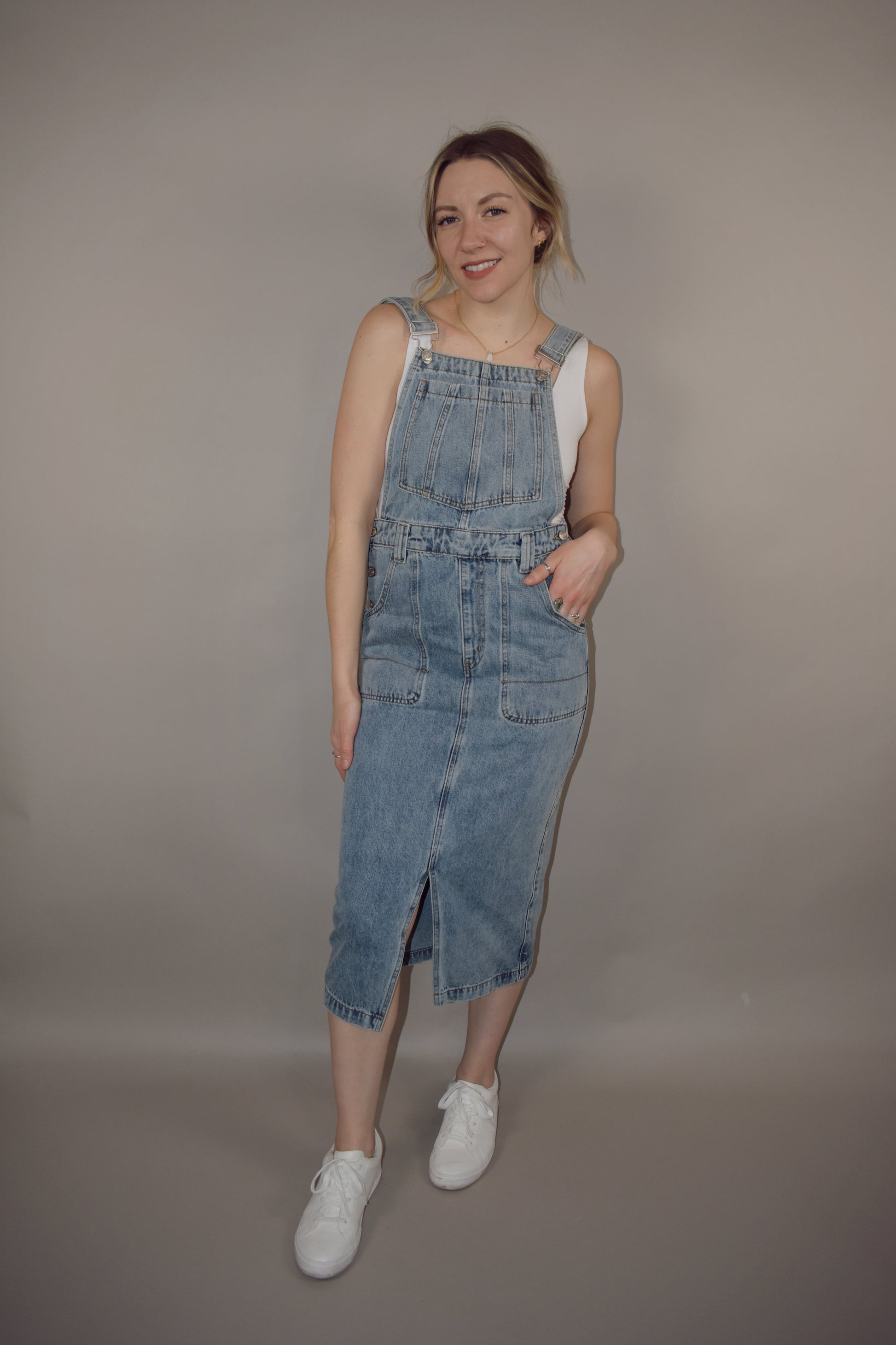 light wash denim overall midi skirt dress with front slit, square neckline on front and back, adjustable straps, has beltloops, deep front pockets, back pockets, button enclosure on both sides