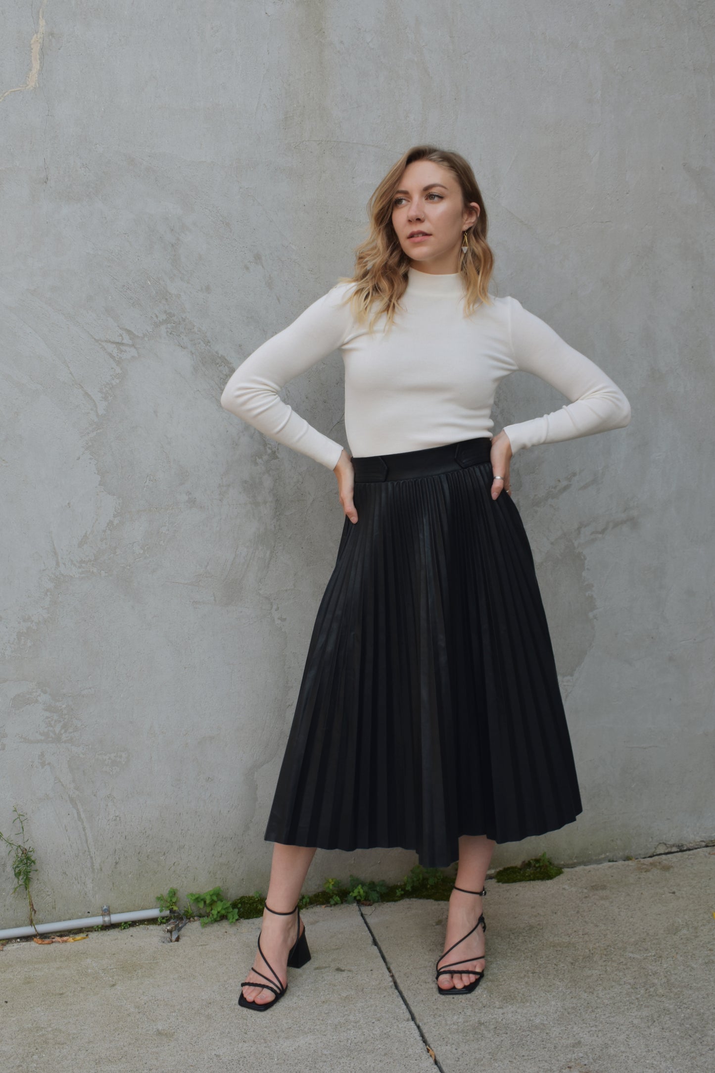 high waisted fully pleated faux leather skirt midi length waist band has tab detailing back of waistband has elastic in band for stretch and it has an invisible zip enclosure on the side