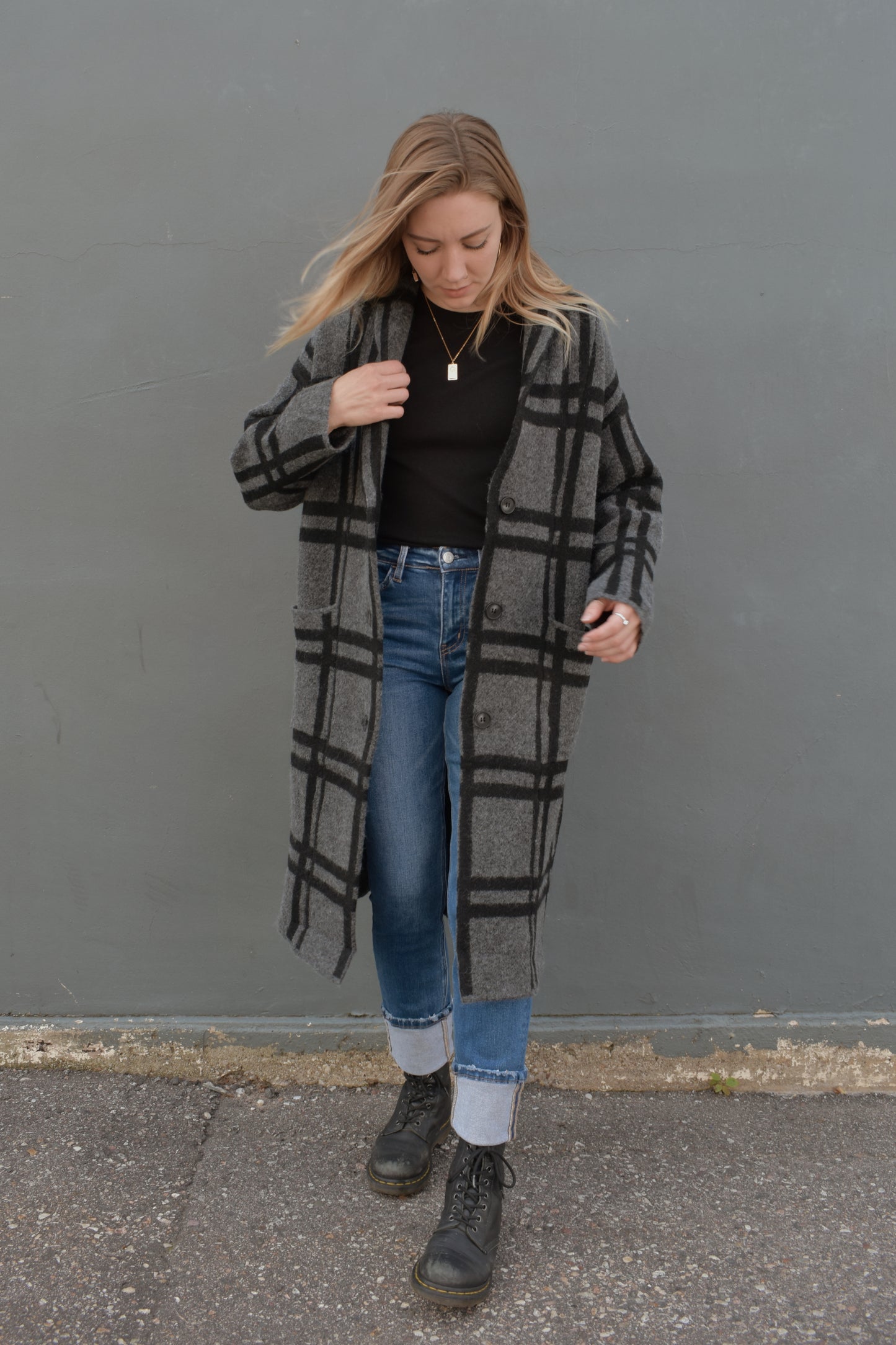 black and grey wide pattered plaid jacket that feels like a cardigan and coat mix, front patch pockets, 3 front buttons for enclosure, folded collar, slightly oversized, drop shoulder, hits at mid calf.