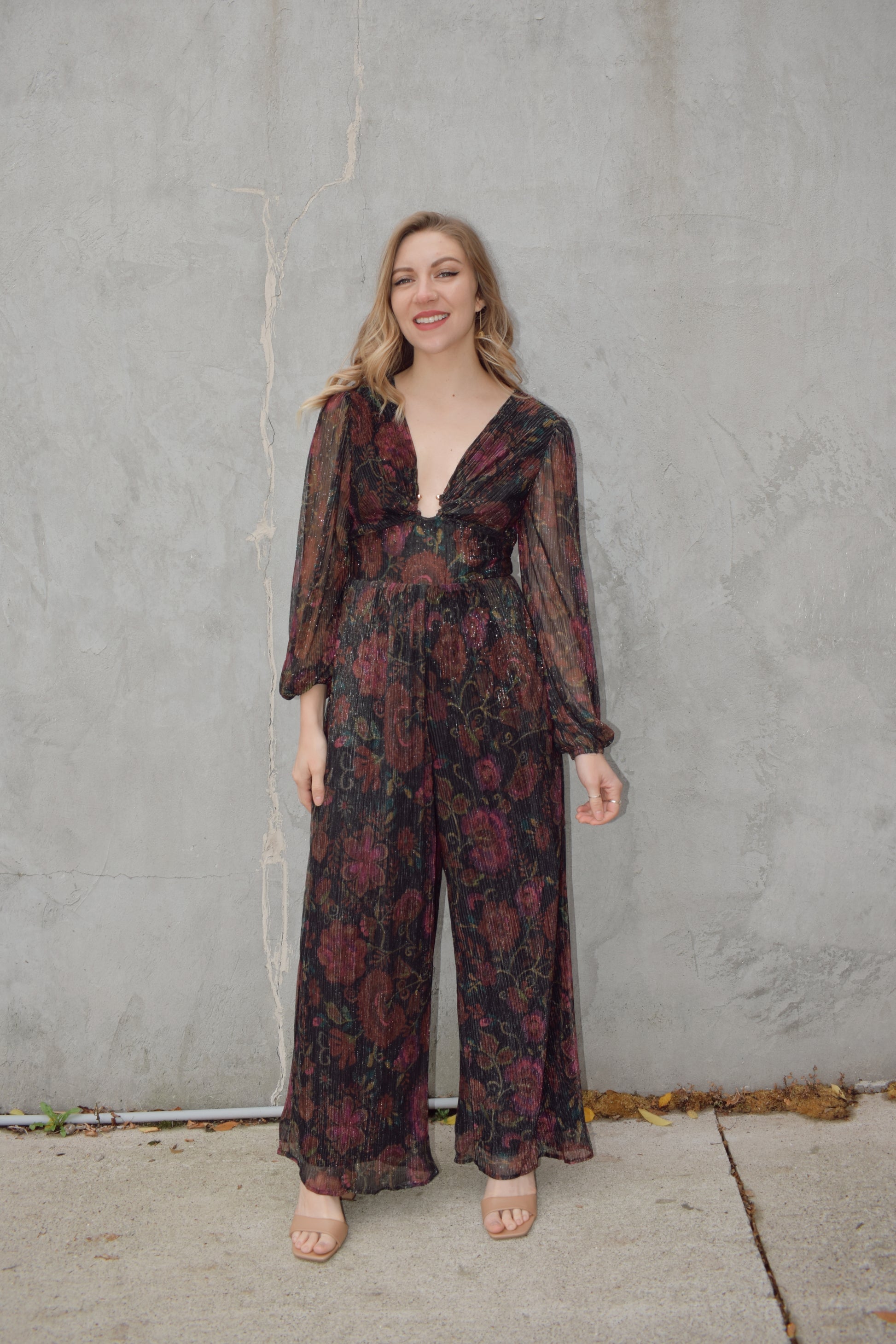 stunning wide leg jumpsuit with fitted bodice panel and deep v neck with circular metal piece at sternum. sheer long sleeves with elastic at cuffs. zip back enclosure