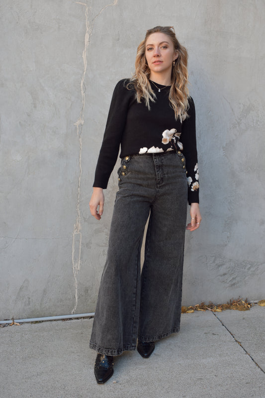 wide leg jeans - black wash - no holes - gold sailor buttons along front side pockets and on button on back belt loop fastening it. zip and button enclosure. high waisted. 