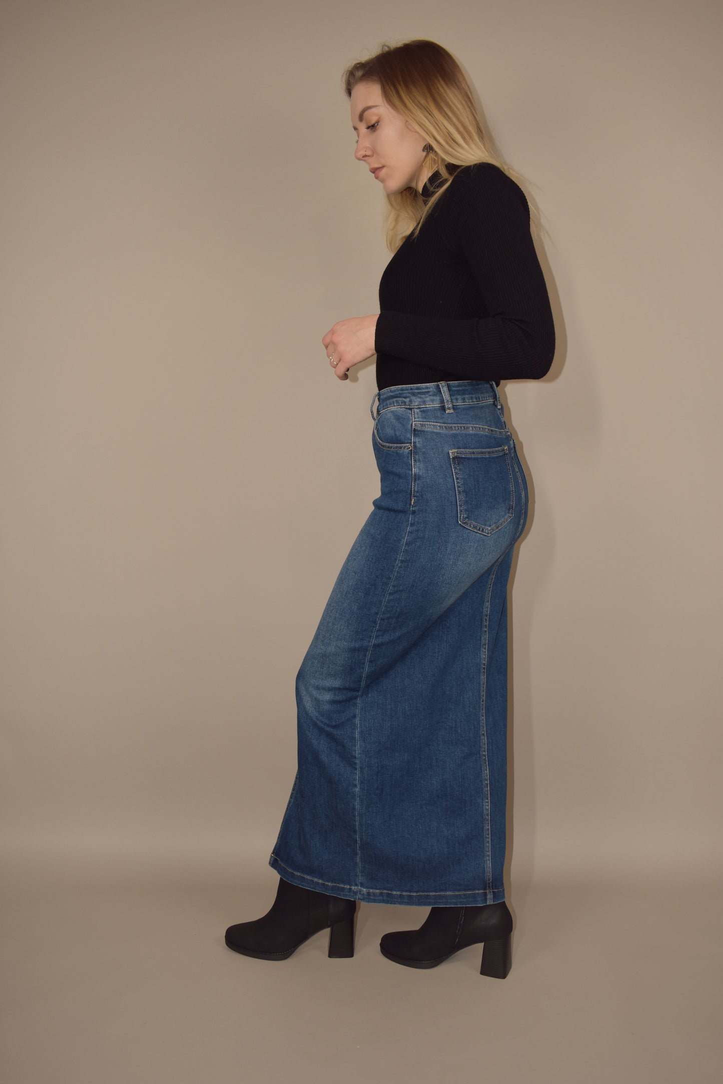 denim midi skirt that is more full length than midi and has a front slit with front and back pockets and is high waisted. made of stretch denim and is a medium dark wash.