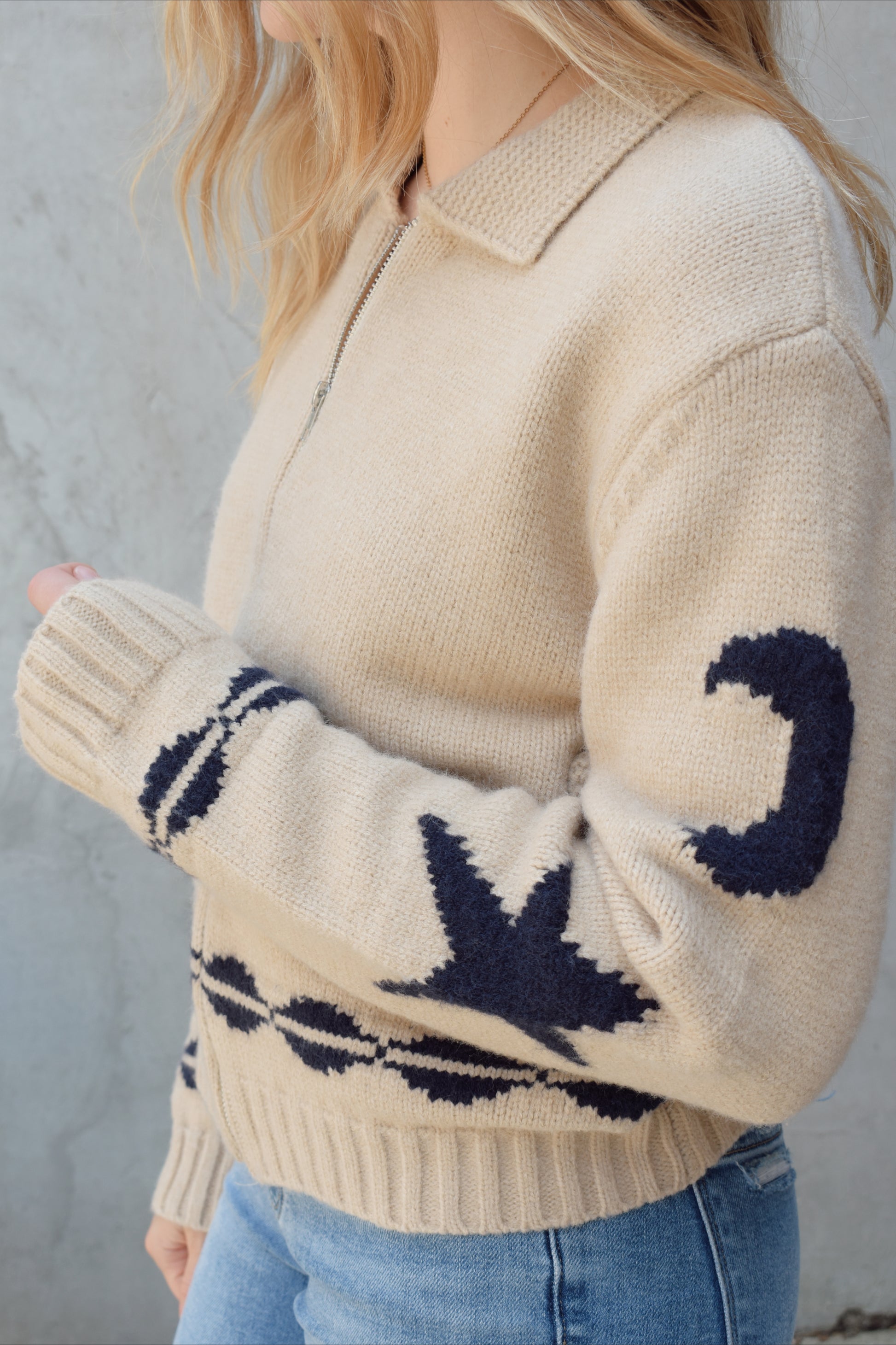 cream zip up sweater jacket with dark blue moon and stars on sleeves and trim design, collared neckline, ribbed hem and cuffs, side pockets, drop shoulders, relaxed fit