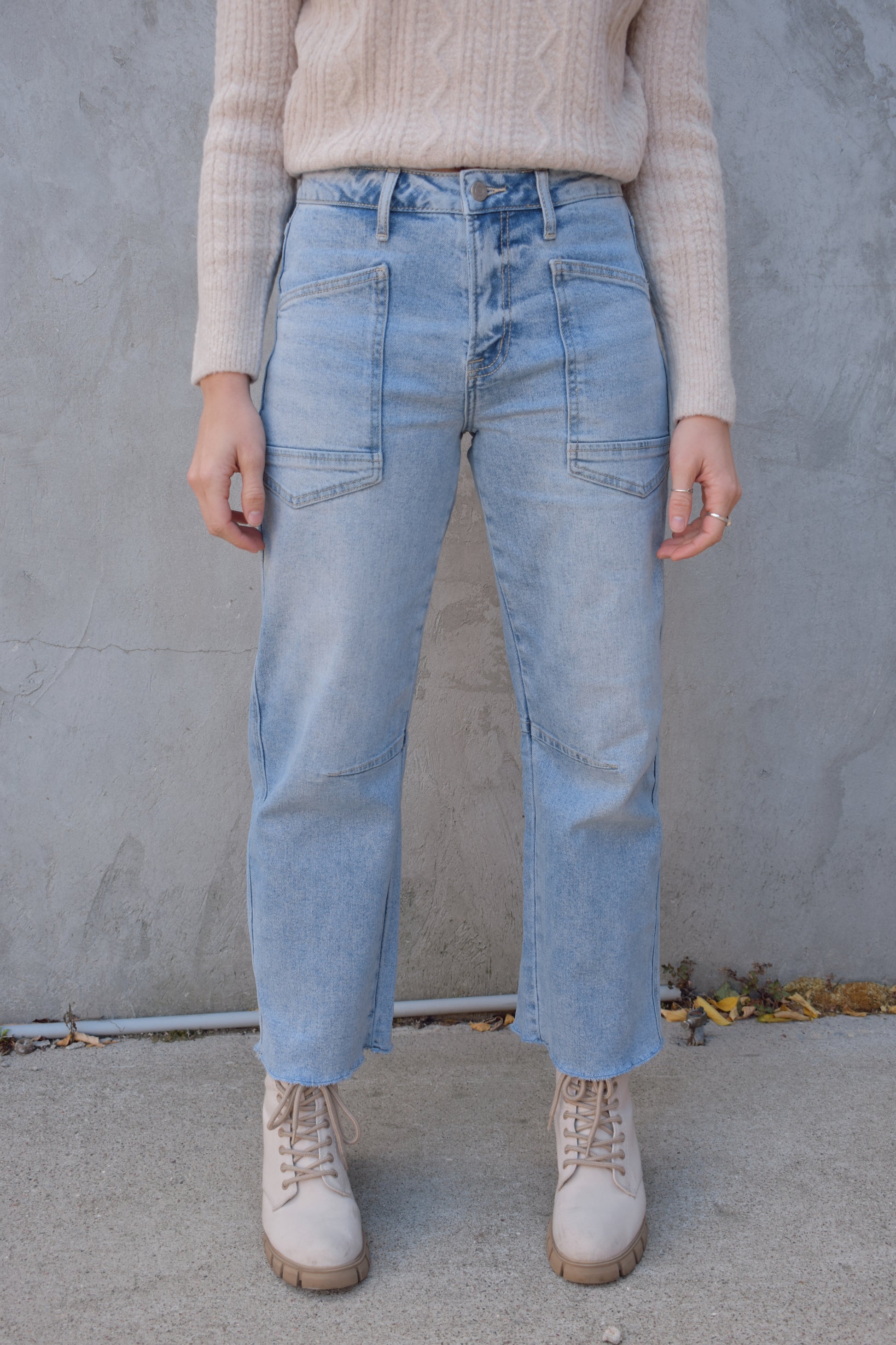 high rise barrel jeans, light wash, stretch denim, no holes, patch pockets in front, back pocket on right has a double pocket detail, zip and button enclosure, has belt loops, raw hem cropped, edgy seam detail at knee