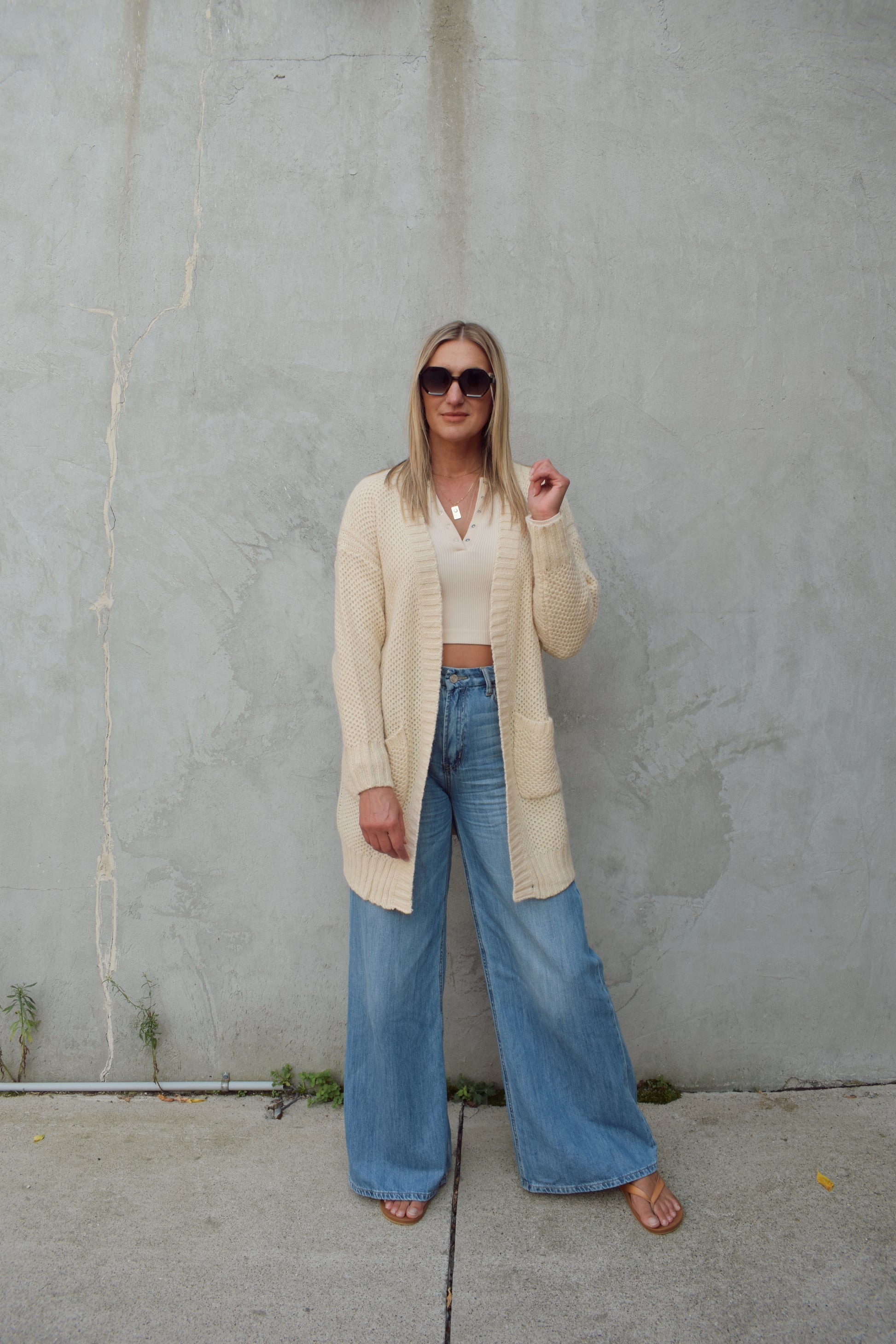 cream cardigan with front patch pockets, hangs straight , ribbed trim and hits mid thigh