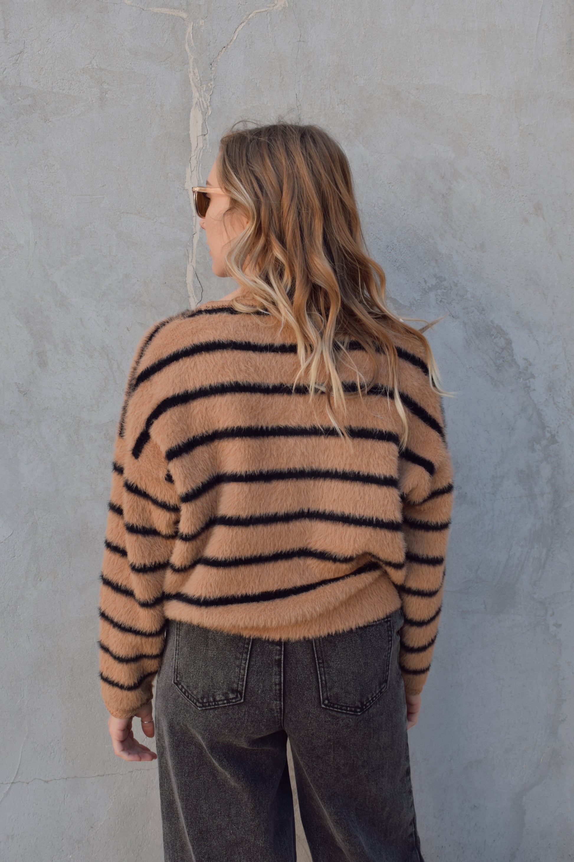 light brown mohair v neck button down cardigan with light brown sailor buttons and black horizontal stripes. two pockets on front that open at the top. outlined with a braided texture on neck line and down the front and on edge of pockets. drop shoulders, slightly cropped.