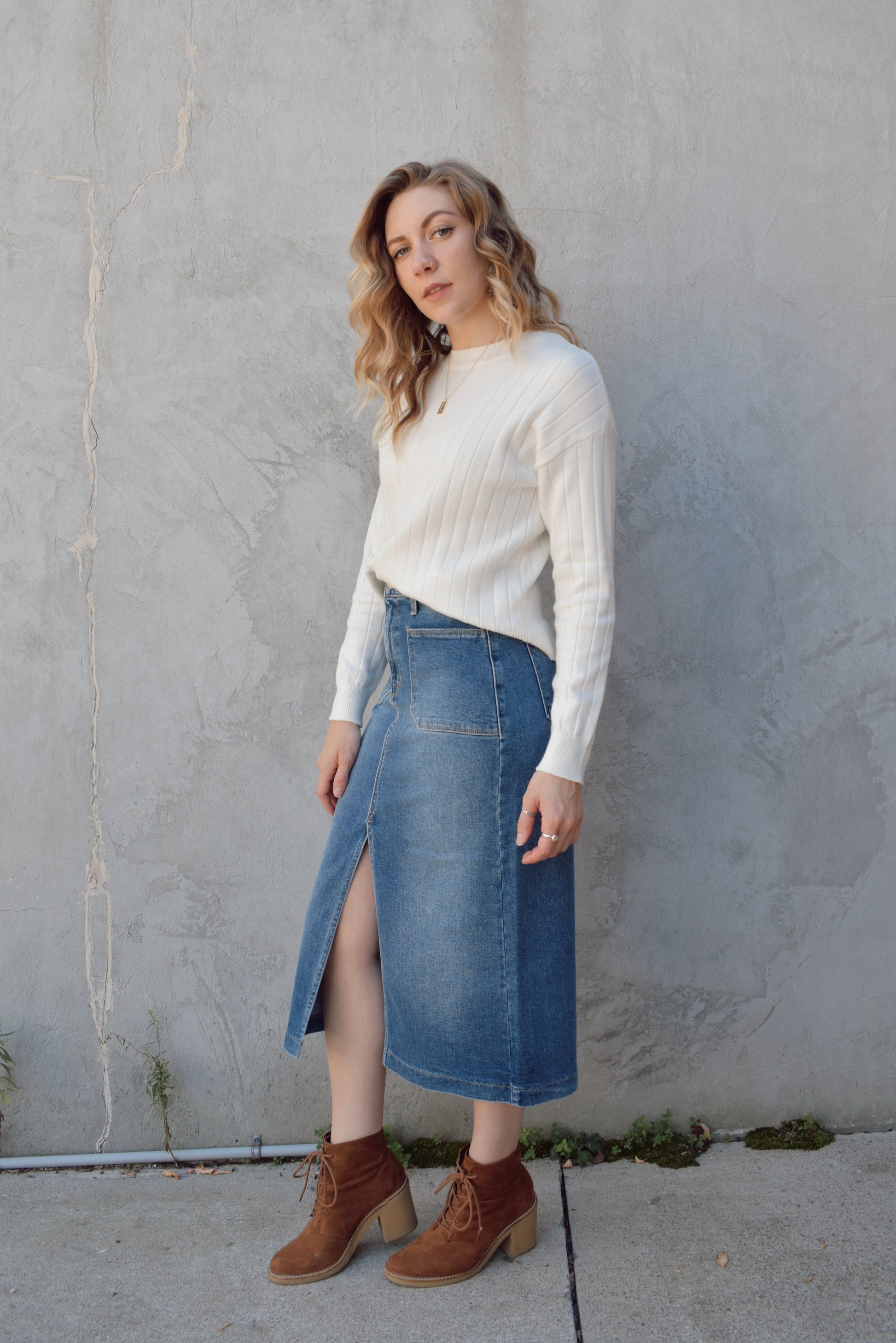 medium to light wash denim midi skirt with front slit, front patch pockets, zip and button enclosure, beltloops, back pockets, no distressing.