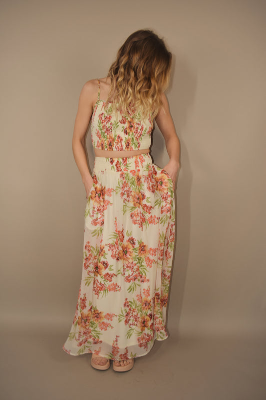 Cream base with a floral print (green, orange, pinks) 2 piece set. Flowy maxi skirt with pockets. Stretchy smocked waist band. Spaghetti strap smocked crop top.