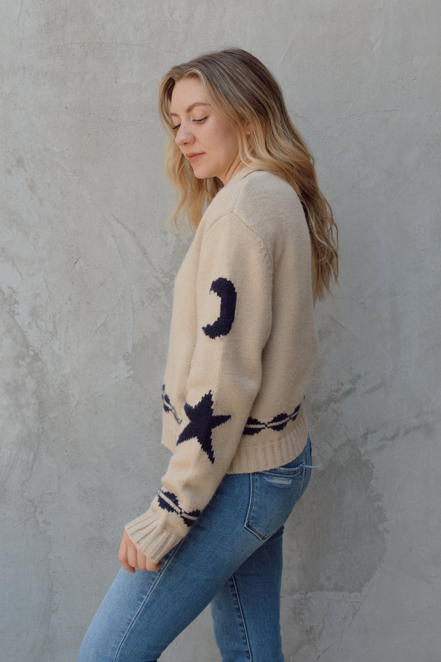 cream zip up sweater jacket with dark blue moon and stars on sleeves and trim design, collared neckline, ribbed hem and cuffs, side pockets, drop shoulders, relaxed fit