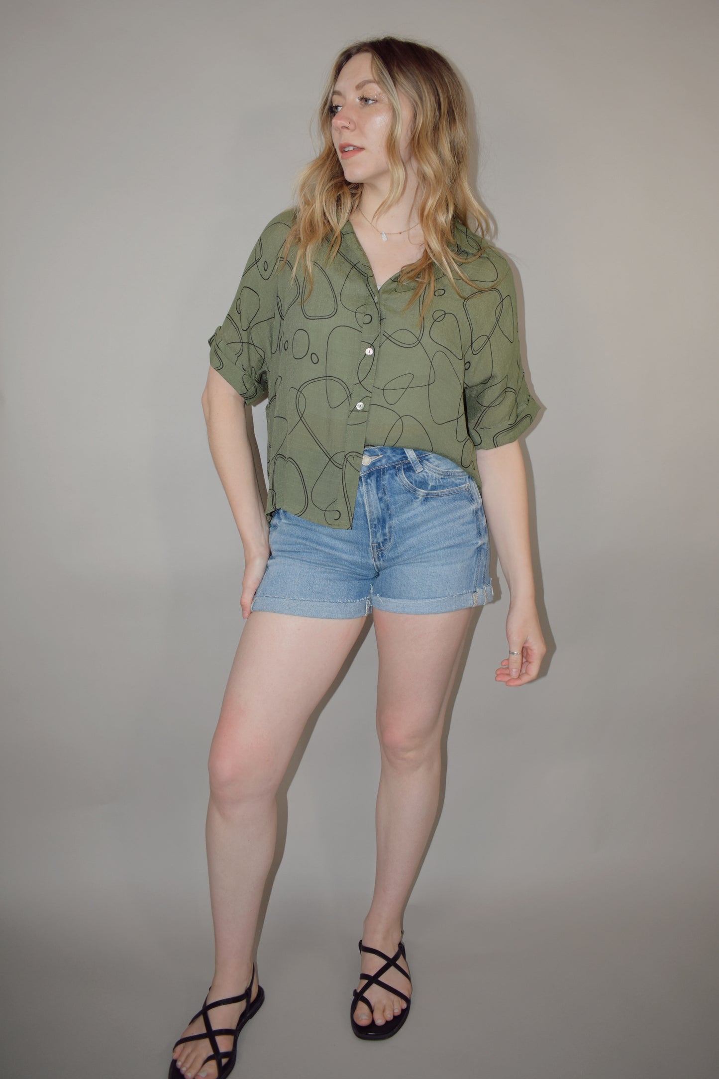 olive green short sleeve button down with black geo print, flowy fit, slight high low hem, cuffed sleeves, very lightweight